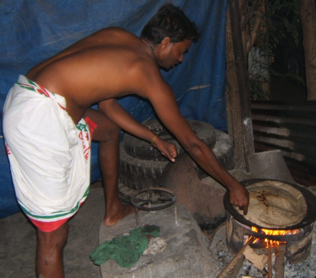 East Indian man helping to bake Aapas (roti)